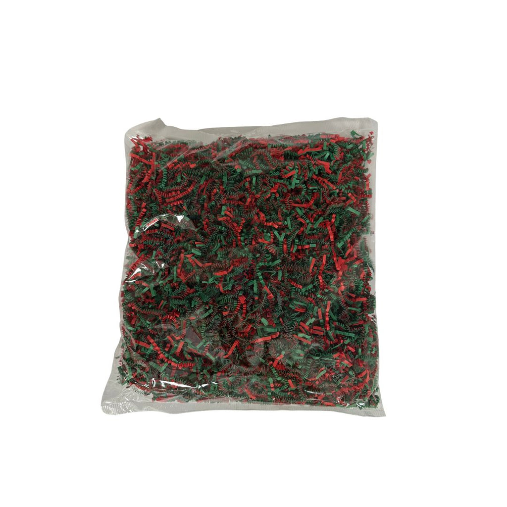 A clear bag filled with shredded Christmas paper in red and green, photographed against a plain white background.