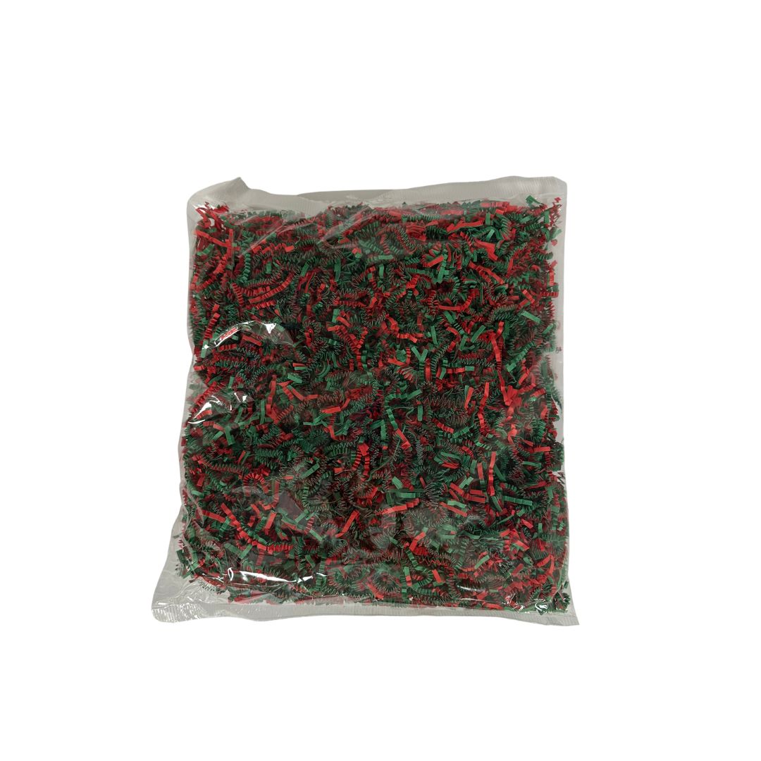 A clear bag filled with shredded Christmas paper in red and green, photographed against a plain white background.