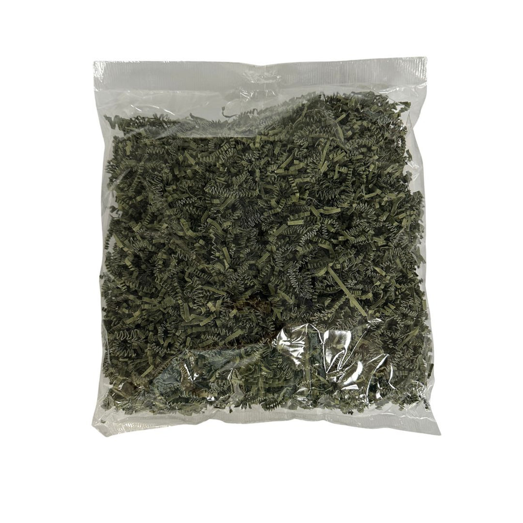 A clear plastic bag filled with dried green filler paper, photographed against a plain white background.