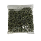 A clear plastic bag filled with dried green filler paper, photographed against a plain white background.