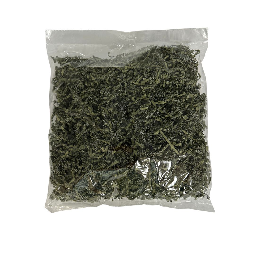A clear plastic bag filled with dried green filler paper, photographed against a plain white background.
