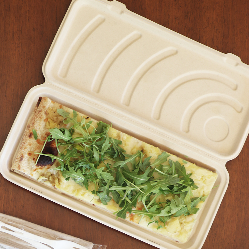Compostable flatbread clamshell with food inside, sitting on a wooden table.