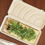 Compostable flatbread clamshell with food inside, sitting on a wooden table.