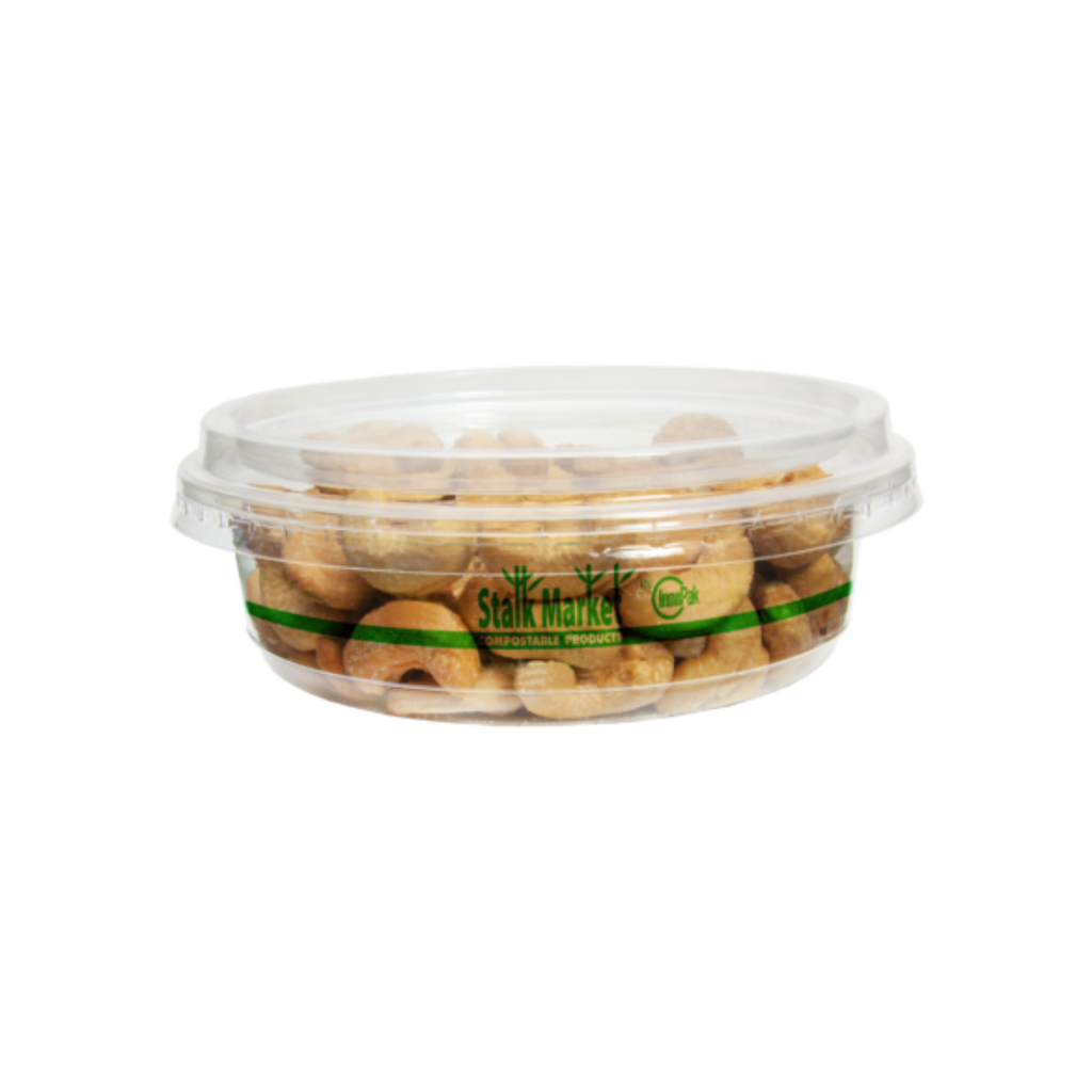 Deli container with lid filled with cashews on a plain background.