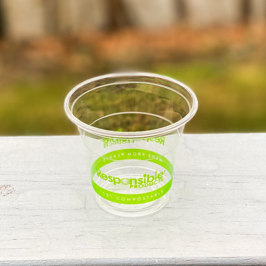 Clear compostable cup with green printing on a wooden table