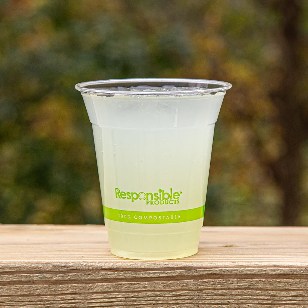 Clear compostable cup with green text, filled with lemonade, on a white background