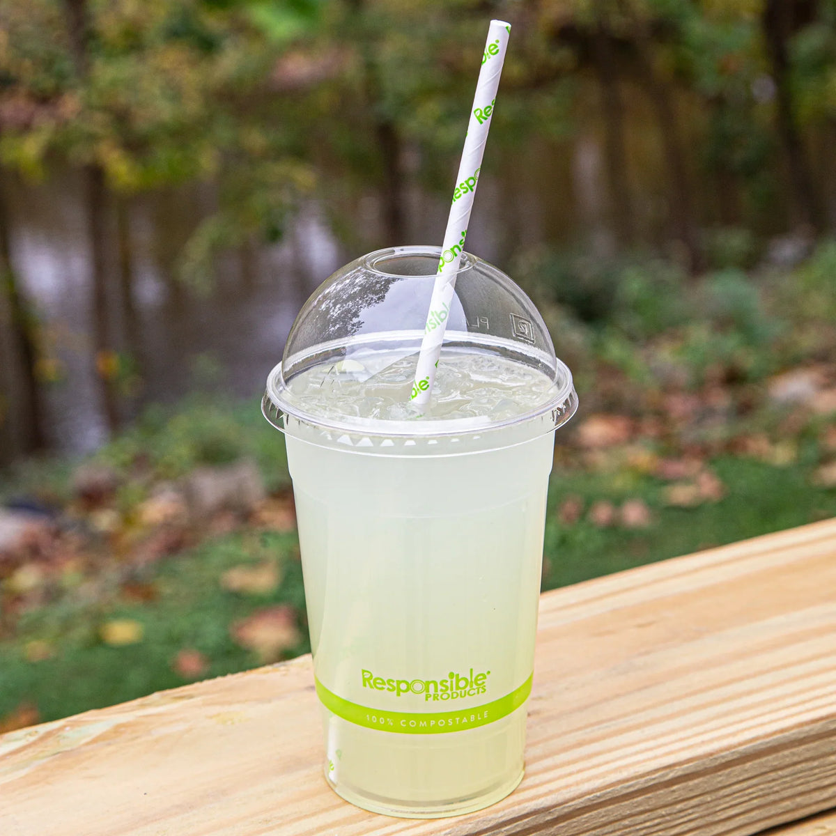 Lemonade in a compostable cup with a dome lid and straw with 'Responsible' branding on a green background