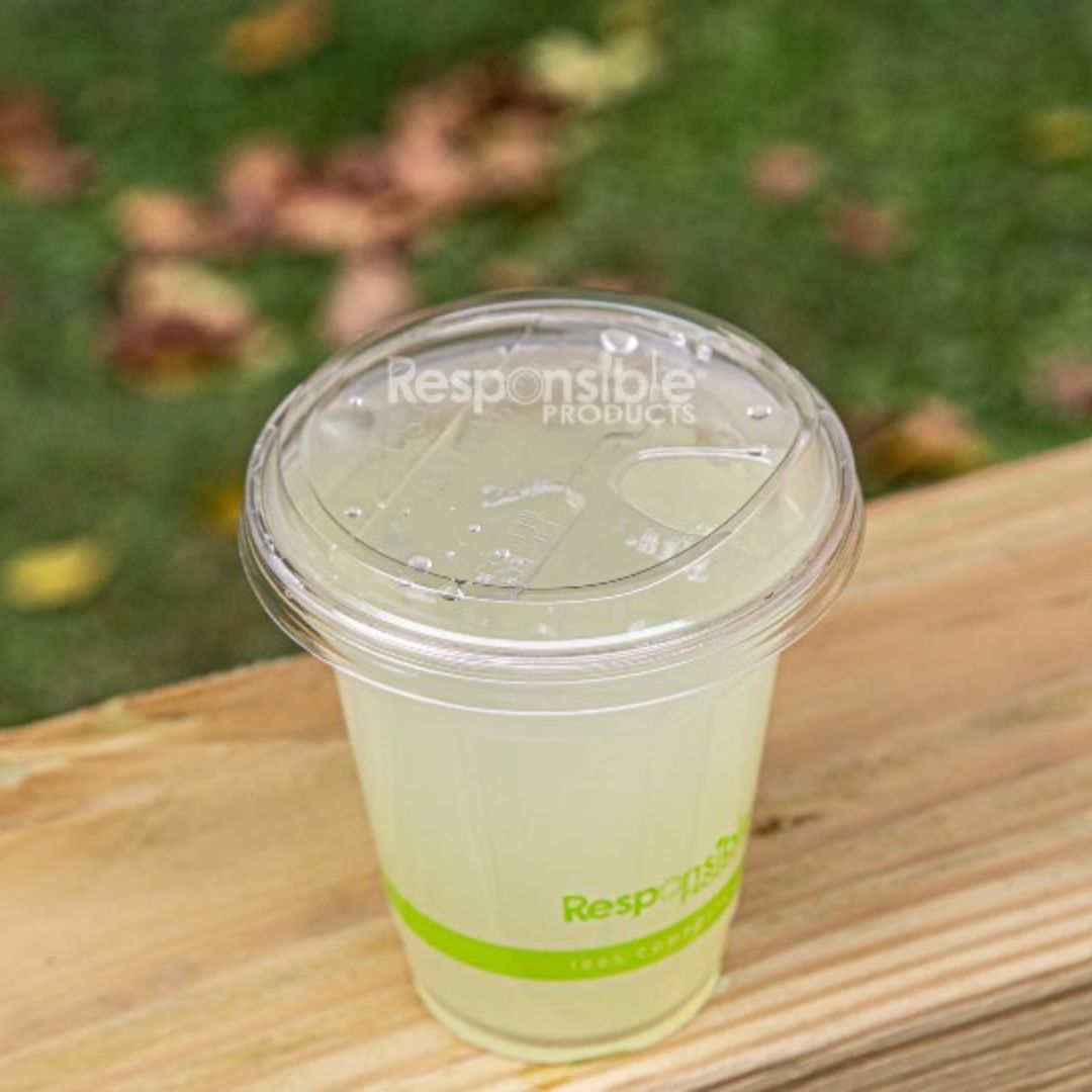 Clear plastic cup with green drink on a wooden surface, branded 'Responsible Products'.