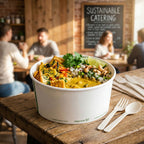Veggie bowl in a white container on a wooden table with sustainable catering sign in the background