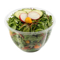 Clear salad bowl with greens, cucumbers, radishes, and cherry tomatoes on a white background