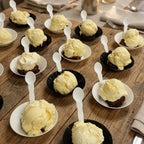 Yummy ice cream dessert on a wooden table in compostable bowls with spoons.