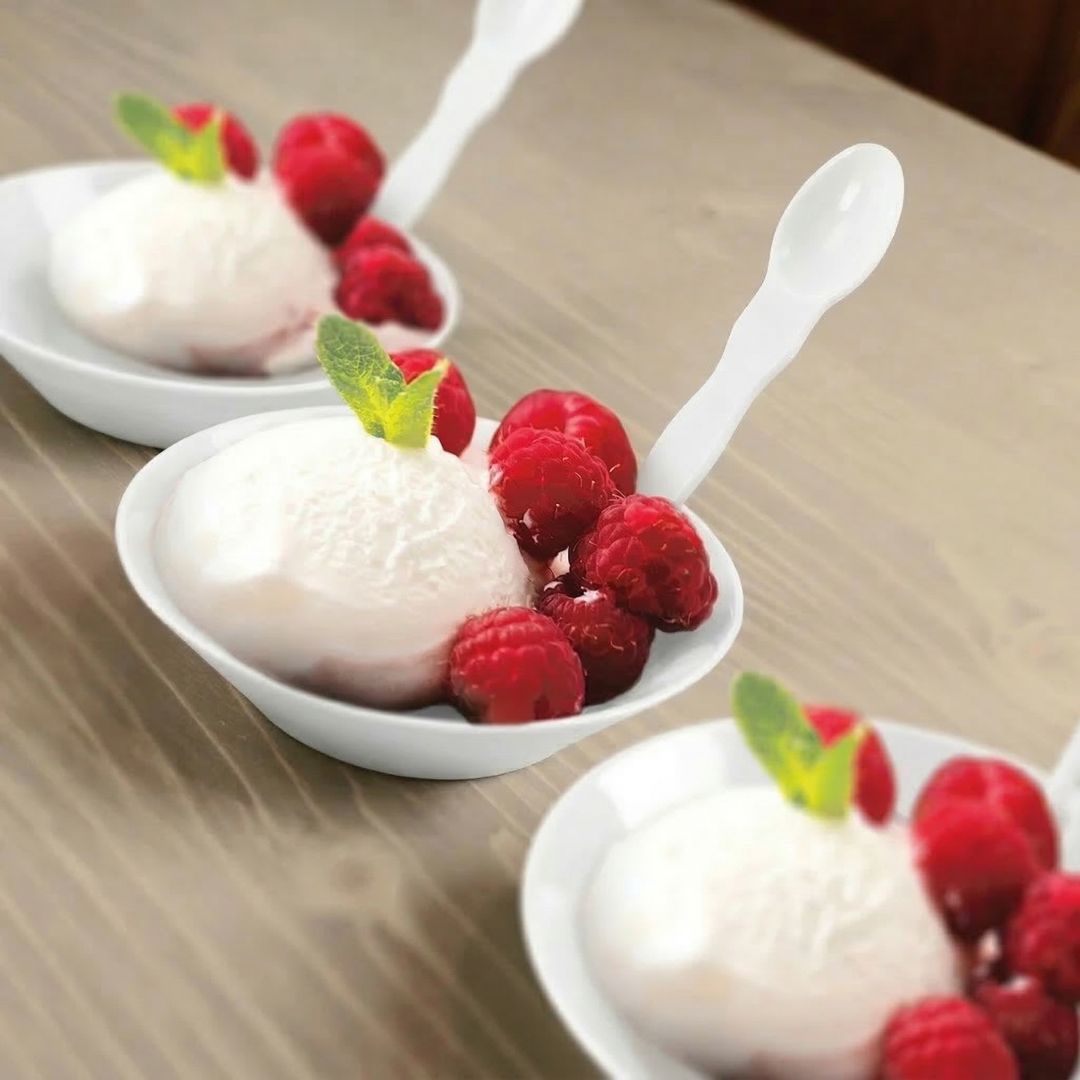 Bowls of dessert with ice cream and raspberries in compostable bowls on a wooden table