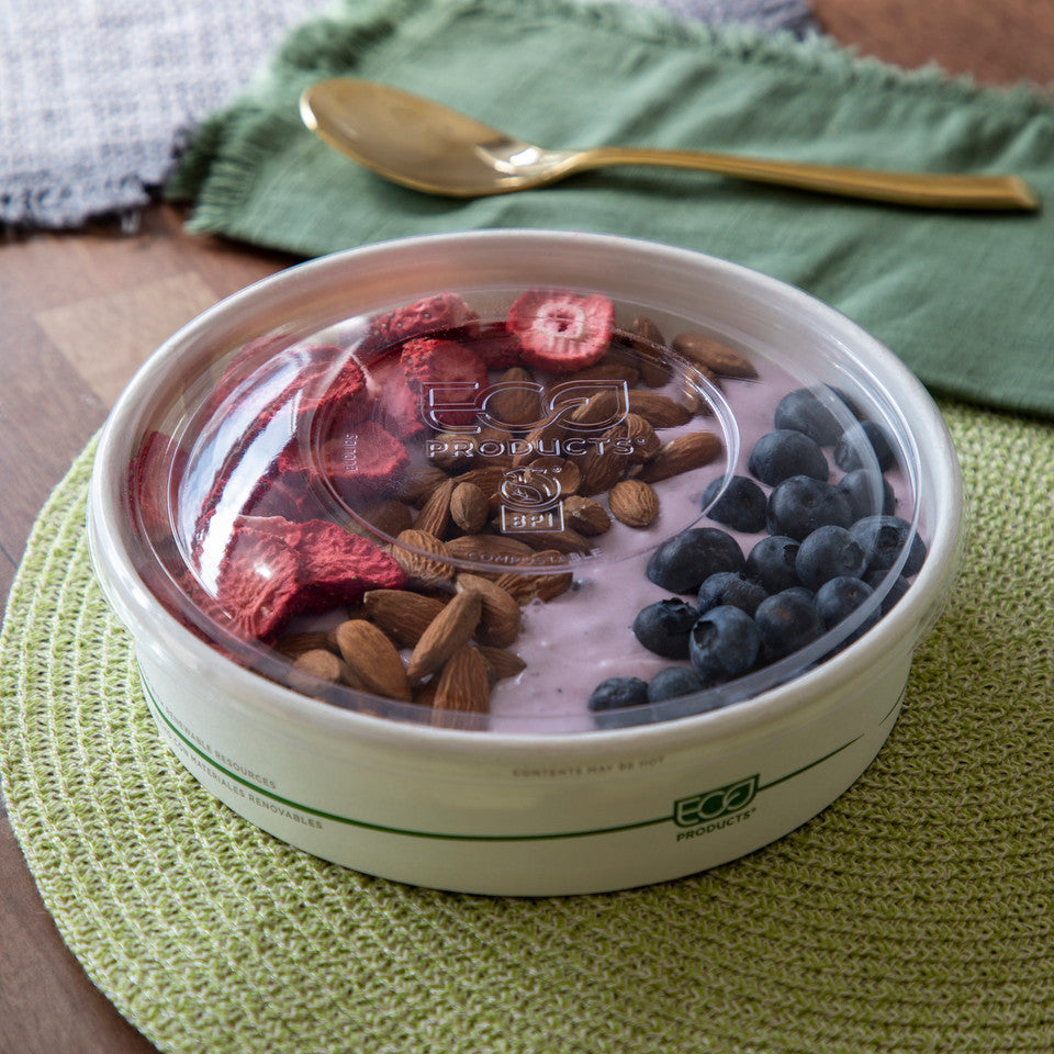 Yogurt bowl with berries and nuts on a green mat with a spoon in the background