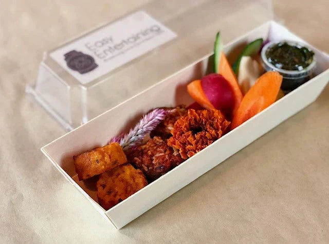 Assorted snacks in a food box with lid on a beige background