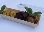 Box of assorted cookies with a clear lid on a white background