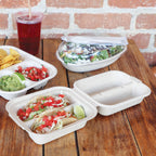 Tacos in a takeout taco container next to a nacho tray and burrito bowl with lid.