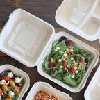 Disposable food container with lid filled with salad.