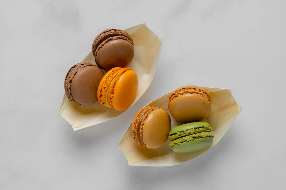 Colorful macarons in paper cones on a light gray background