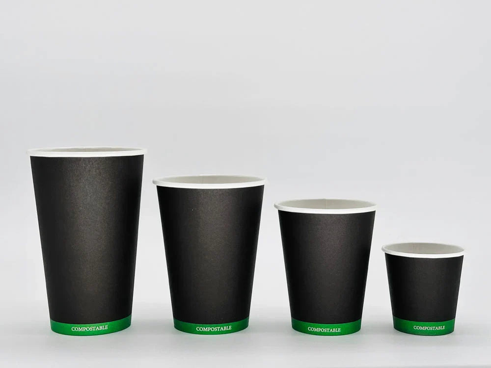 Set of four black paper cups with green labels on a white background
