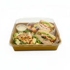 Square tray with a clear lid containing salad, grilled chicken, and sandwiches on a white background