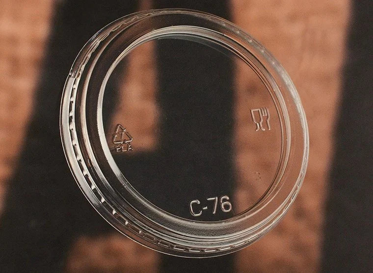 Clear plastic lid with recycling symbols and text on a brown background