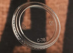 Clear plastic lid with recycling symbols and text on a brown background