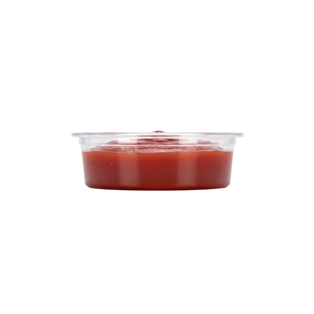 A compostable portion cup with ketchup, shown against a plain white background.