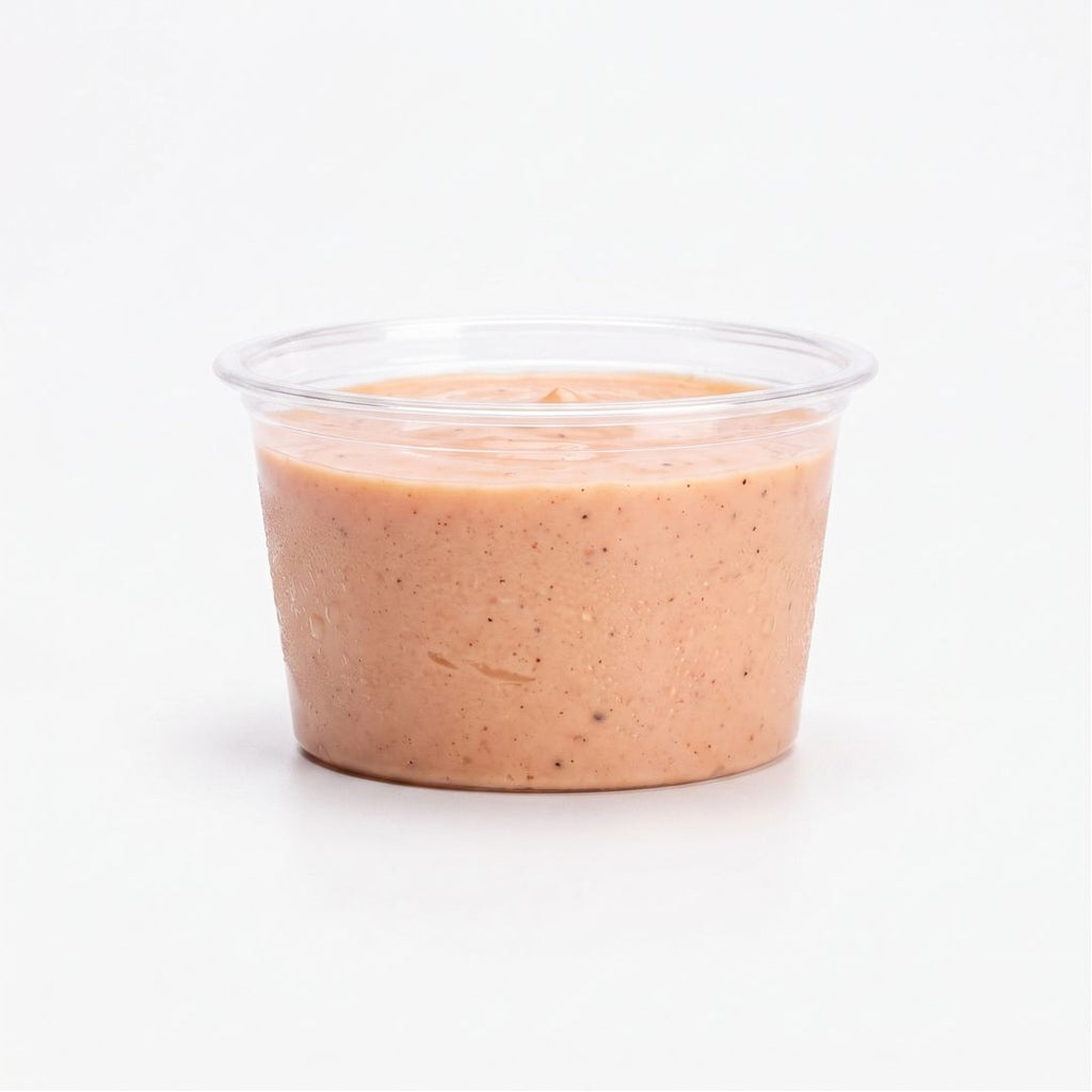 A small clear portion cup filled with fry sauce, photographed against a clean white background.