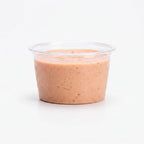 A small clear portion cup filled with fry sauce, photographed against a clean white background.