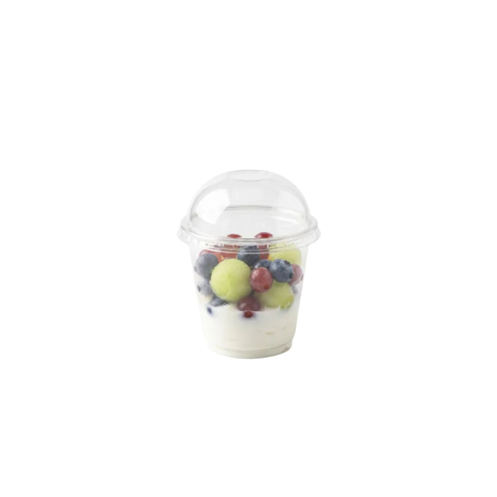 A clear portion cup with dome lid, filled with white yogurt and topped with mixed fresh fruit including grapes, berries, and a melon, isolated on a white background.