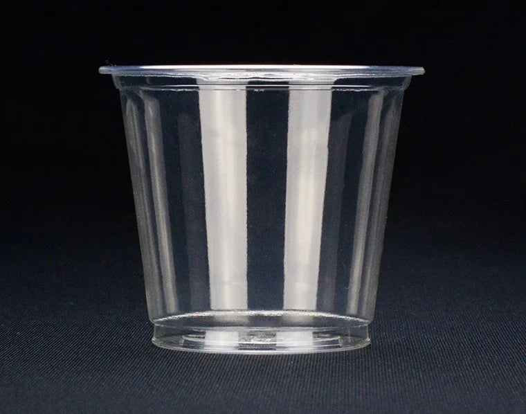 A compostable portion cup with a flared rim, shown on a dark textured background.