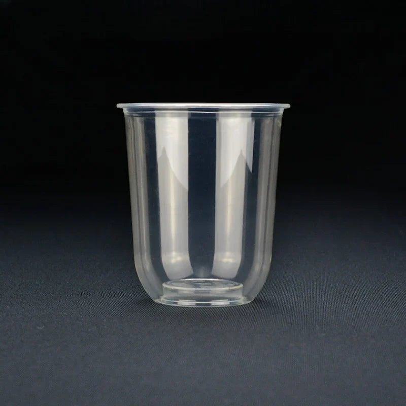 A clear bubble tea or iced coffee cup, shown on a dark gray textured surface against a black background.