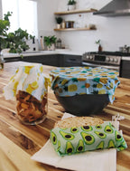 Reusuable fabric food wraps on jars and a bowl in a kitchen setting