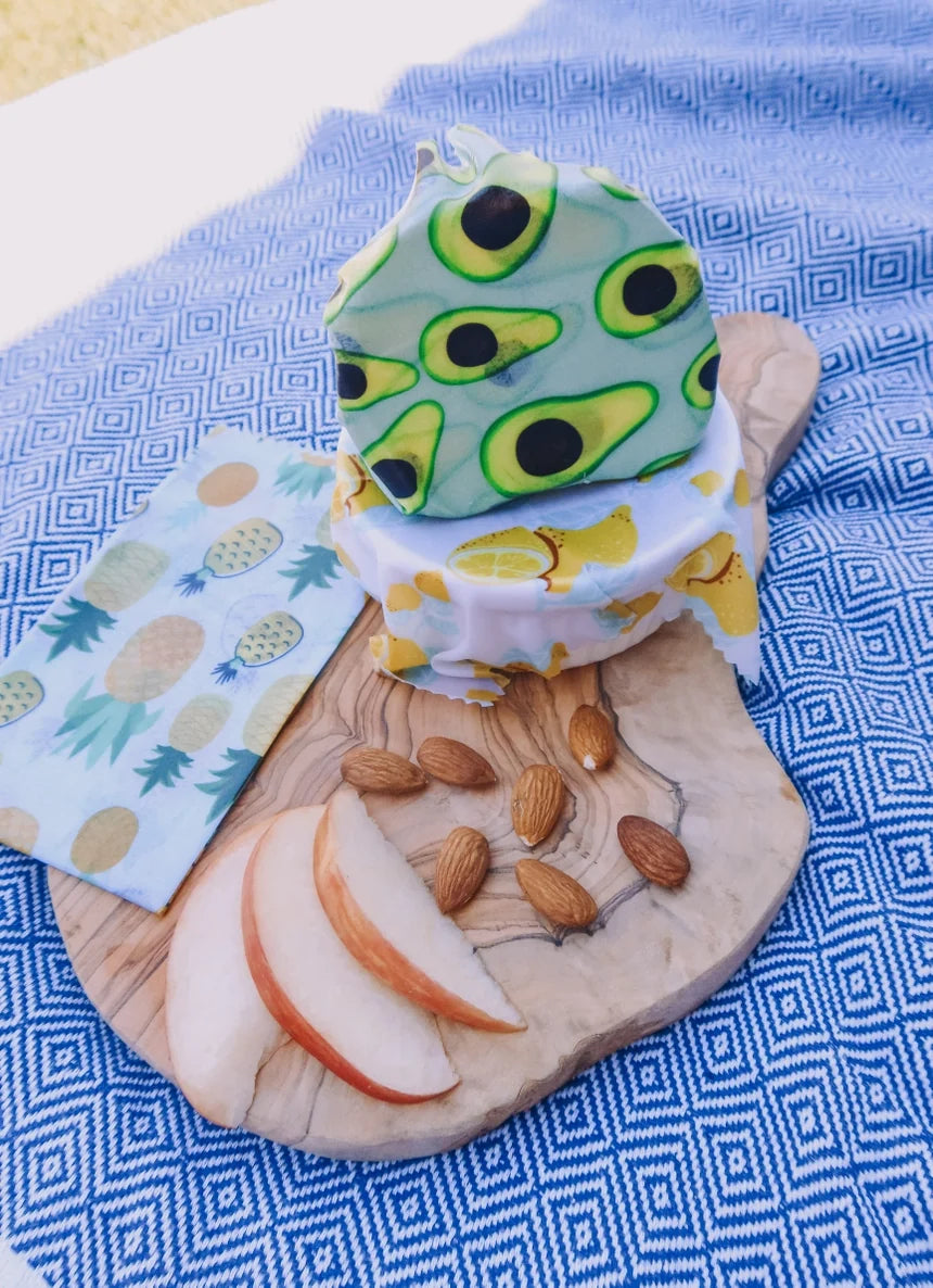 Food-themed wax food wraps on a wooden board with fruits and nuts