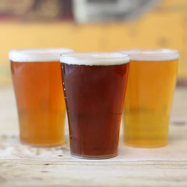 Three disposable glasses of beer on a wooden surface with a blurred background