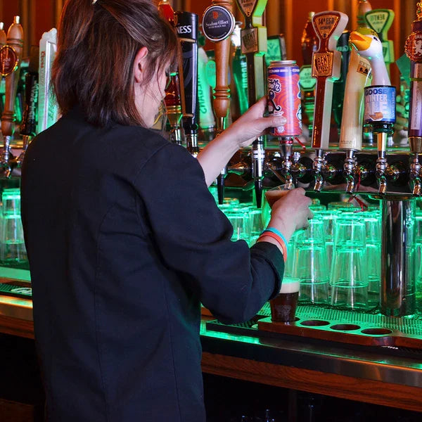 Person at a bar pouring a beer into a compostable beer tasting cup.