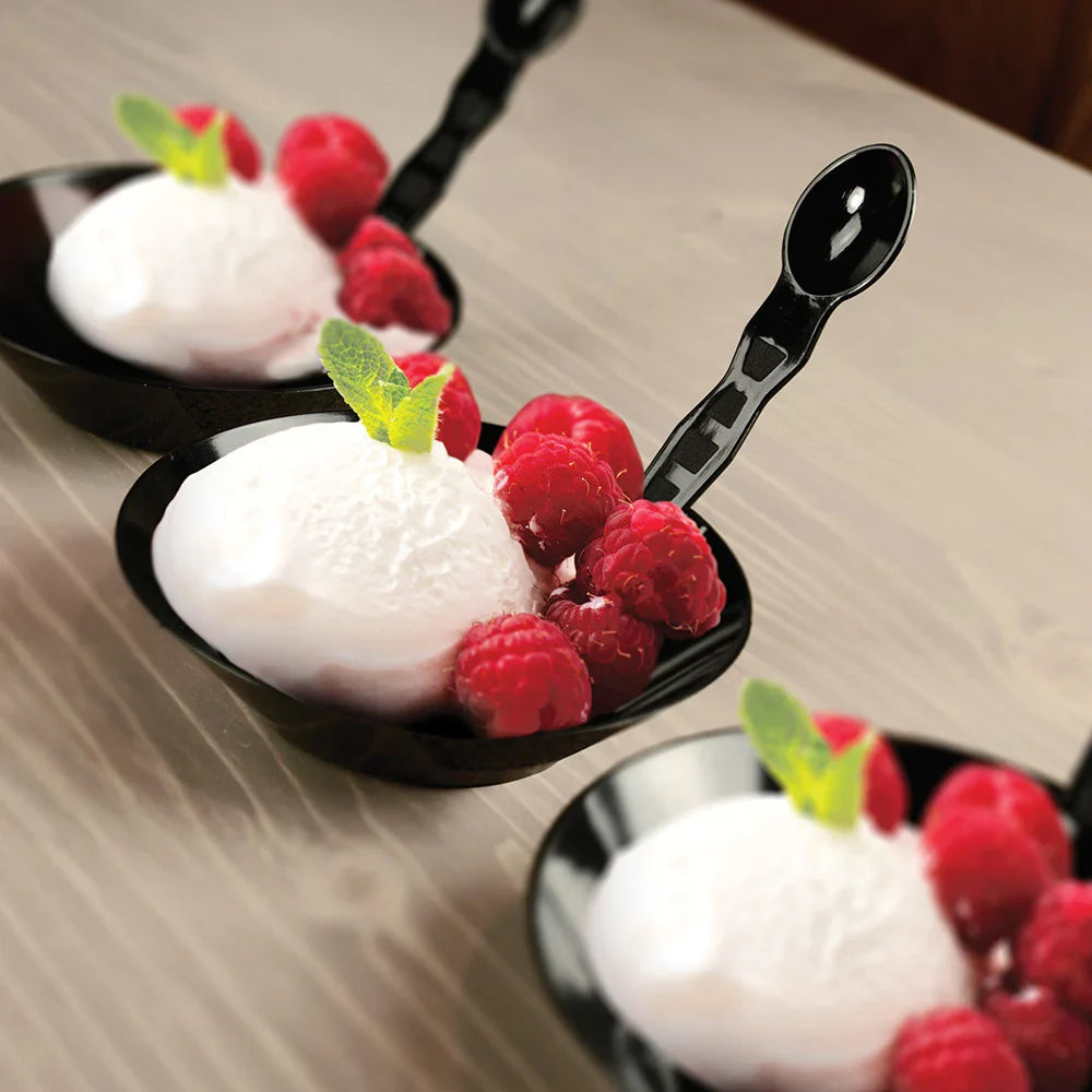 Black spoons with dessert and raspberries on a wooden surface