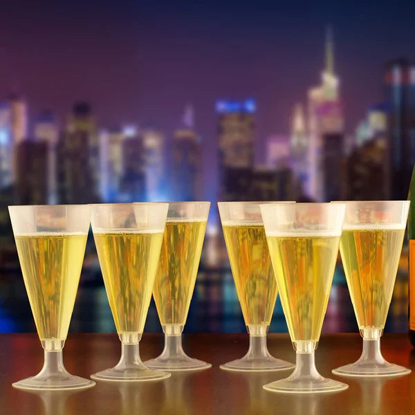 Five glasses of champagne in compostable cups on a table with a city skyline in the background