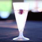 Clear champagne glass with a white liquid and a berry on a dark surface