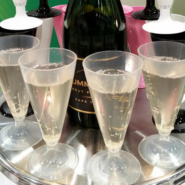 Compostable champagne flutes with champagne on a tray, with a bottle of champagne in the background.
