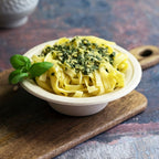 Compostable tan bowl containing noodles on a cutting board.