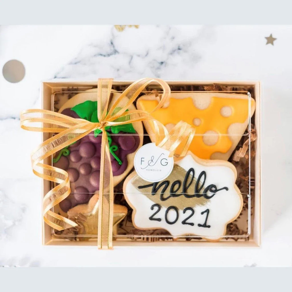 Gift box with decorative cookies featuring a 'hello 2021' message on a marble surface.