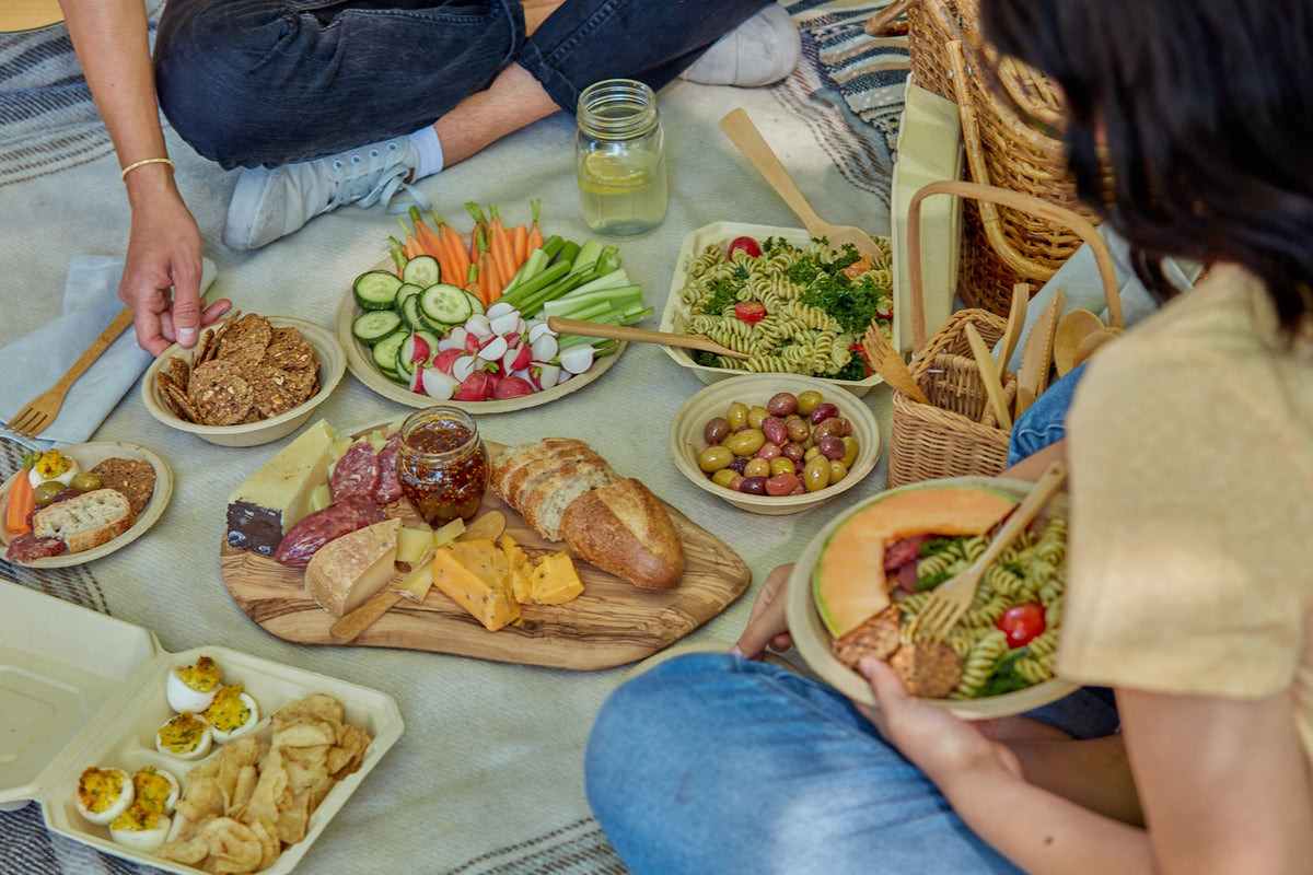 Compostable tableware including plates, clamshells, and bowls being used for Charcuterie.