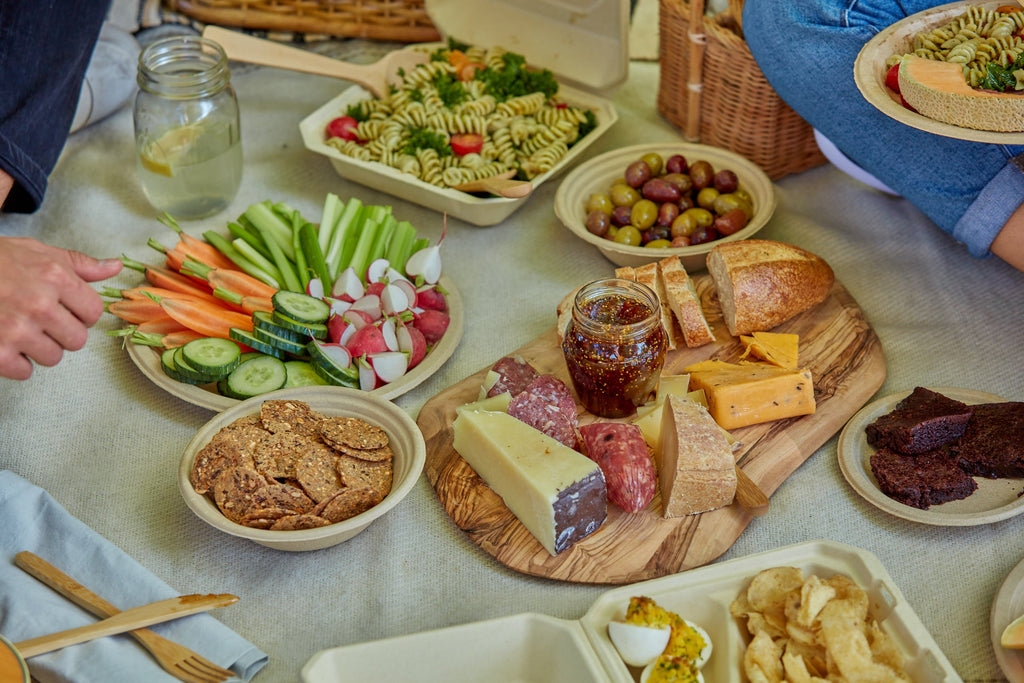 Compostabe bowls, plates, and clamshells being used for picnic food.