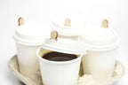 White hot cups with wooden coffee cup plugs in a cup carrier.