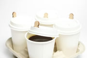 White hot cups with wooden coffee cup plugs in a cup carrier.